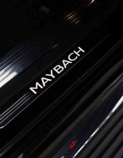 Close-up of illuminated 'MAYBACH' door sill branding on a custom Mercedes SUV, built for luxury or executive-level protection.