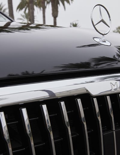 Front hood and grille detail of a black Mercedes-Maybach SUV featuring chrome emblem and signature Mercedes star ornament.