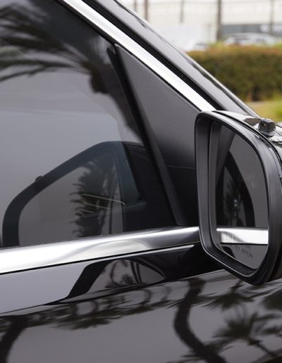 Close-up of driver-side mirror and ballistic glass layering on a black Mercedes-Maybach SUV, built for discreet armored protection by Quality Coachworks.