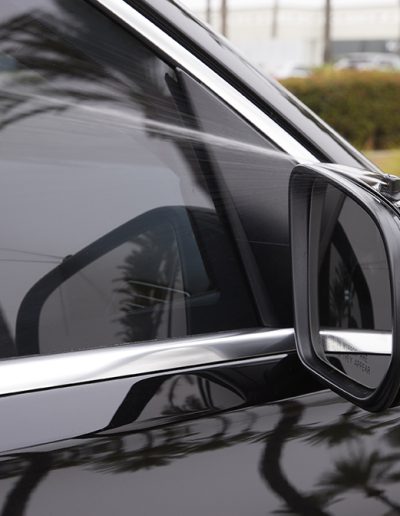 Close-up of driver-side mirror and ballistic glass layering on a black Mercedes-Maybach SUV, built for discreet armored protection by Quality Coachworks.