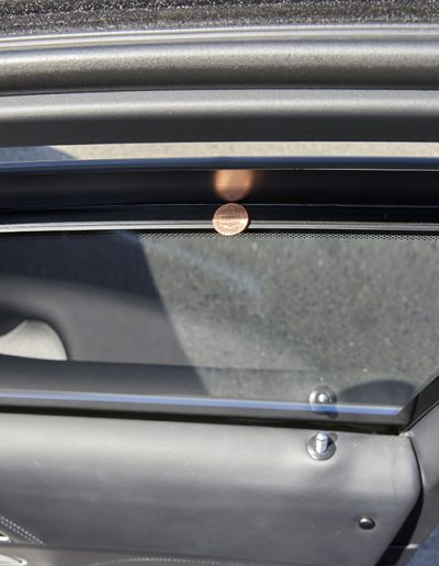 Interior shot showing penny balance test in window track of a Mercedes-Maybach SUV, illustrating the precision fit of ballistic-grade windows.