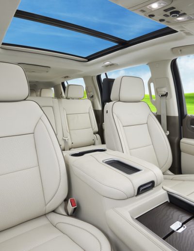 Front Row & Second-row seating inside a custom 6-door GMC Yukon Denali SUV, featuring white leather and panoramic sunroof by Quality Coachworks.