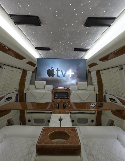Luxury mobile office (CEO) interior inside a Cadillac Escalade SUV, featuring wood trim, ambient lighting, and star-studded ceiling by Quality Coachworks."