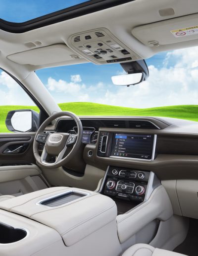 Driver cabin interior of a 6-door GMC Yukon Denali with full leather trim, digital display, and panoramic glass roof.