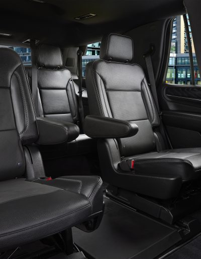 Interior cabin of a 6-door GMC Yukon Denali SUV featuring black leather seating and third-row access, built by Quality Coachworks.