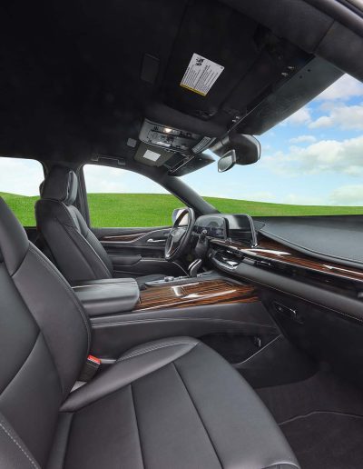Front passenger and driver seating inside a 6-door GMC Yukon Denali SUV, featuring wood grain trim and luxury finishes.