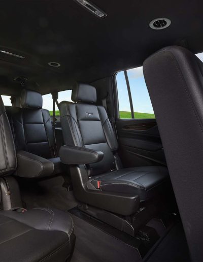 Interior cabin view of a 6-door SUV with multiple rows of black leather seating and overhead lighting, built for executive or group travel.