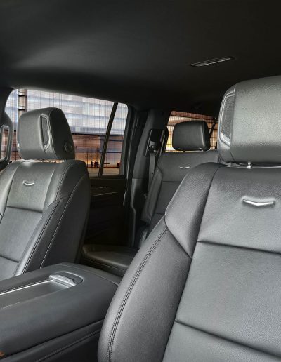 Front captain seats with leather upholstery and wood trim inside a 6-door Cadillac Escalade SUV conversion by Quality Coachworks.