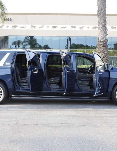 Side view of a blue 6-door Cadillac Escalade SUV with all six doors open, showing extended cabin access and rear legroom.