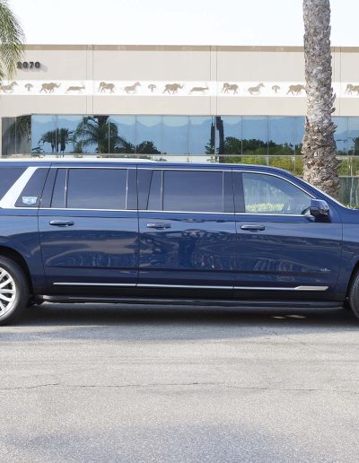 Full side profile of a navy blue 6-door Cadillac Escalade SUV custom-built for executive or VIP group travel.
