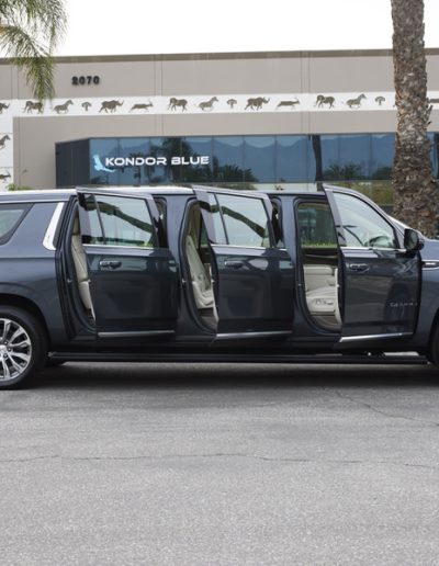 Full side view of a 6-door Cadillac Escalade SUV with all six doors open, displaying custom interior upgrades and extended body