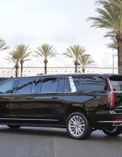 Passenger-side rear angle of a black 6-door Yukon Denali conversion SUV, custom-built for VIP and group travel by Quality Coachworks.