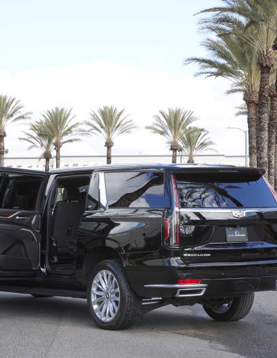 Rear angle of a black 6-door GMC Yukon Denali SUV with all passenger doors open, built for high-capacity transport by Quality Coachworks.