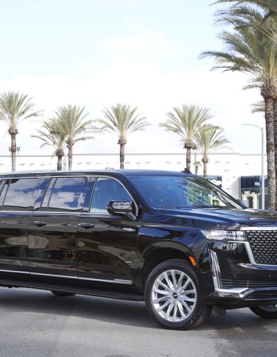 Three-quarter view of a black 6-door Cadillac Escalade SUV conversion with extended body and chrome grille, built by Quality Coachworks.