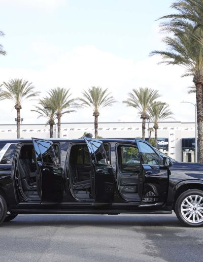 Side profile of a black 6-door Yukon Denali SUV with open doors showing full-length cabin access, custom-built by Quality Coachworks.