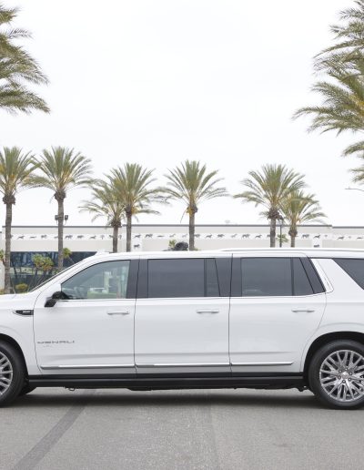 Full passenger-side profile of a white 6-door GMC Yukon Denali SUV conversion, custom-built for high-capacity luxury transport.