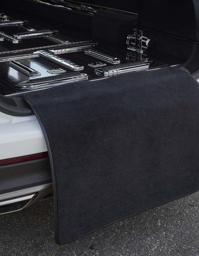 Extended rear cargo bay of a Lincoln Nautilus hearse showing casket rollers and protective carpet mat for funeral transport.