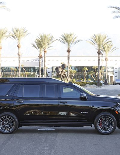 Side profile of a Cadillac Escalade with blacked-out wheels and privacy tint, converted for executive use by Quality Coachworks.