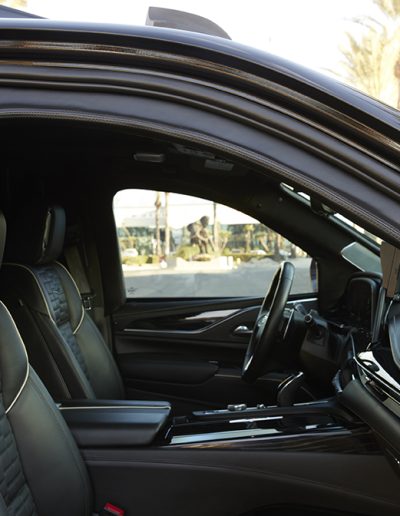 Driver-side cabin view of a Cadillac Escalade SUV interior with leather trim and premium finish, built by Quality Coachworks.
