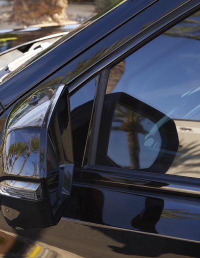 Close-up of armored vehicle side mirror with ballistic glass window layering, custom-built by Quality Coachworks.