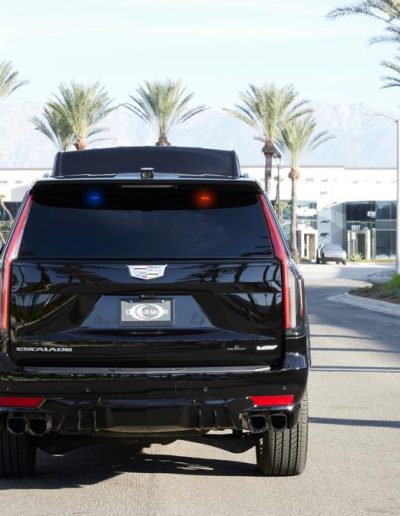Rear exterior view of a black Cadillac Escalade SUV conversion by Quality Coachworks, designed for luxury or secure VIP transport.