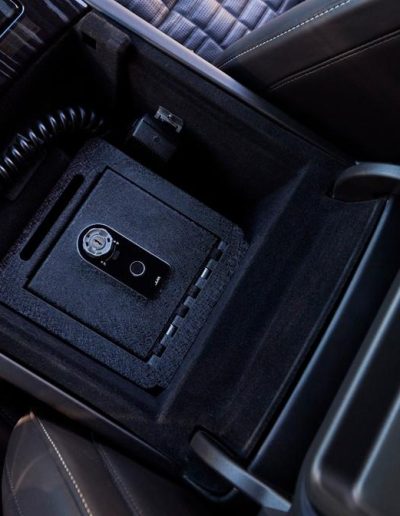 Close-up of a concealed in-console safe in a custom vehicle interior, installed by Quality Coachworks for secure transport.