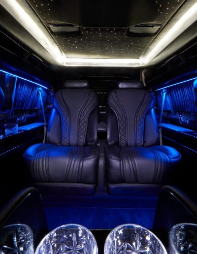 Luxury black leather captain chairs and starlight ceiling in a Cadillac Escalade executive interior conversion by Quality Coachworks.