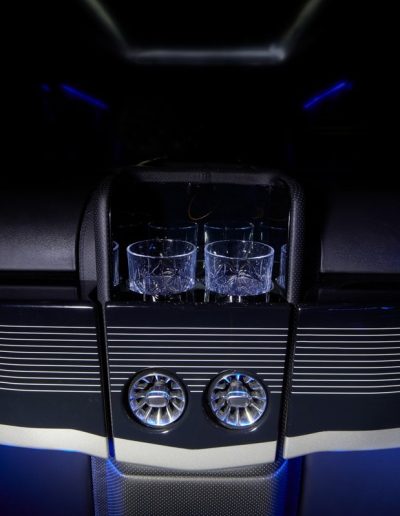 Close-up of a custom bar and refrigerator unit inside a luxury Cadillac Escalade interior conversion with ambient blue lighting.