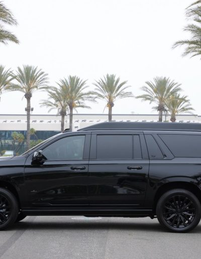 Passenger side view of a custom Cadillac Escalade with blackout package, converted for VIP and executive transport by Quality Coachworks.